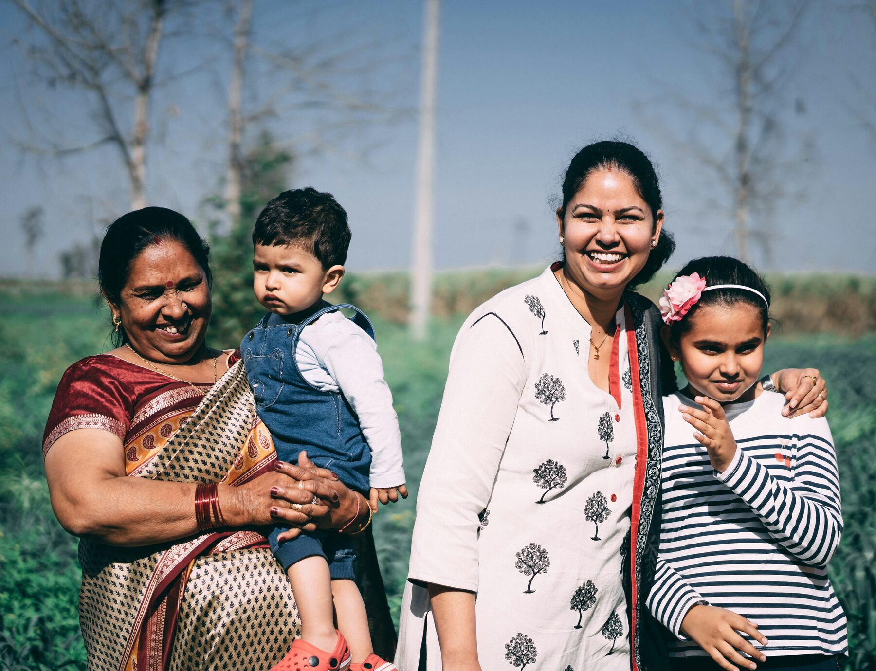 An Indian-American family standing together in a sunlit field